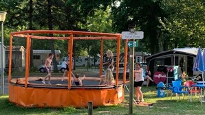 Un trampoline installé à l’extérieur, avec un panneau indiquant un endroit situé à proximité.