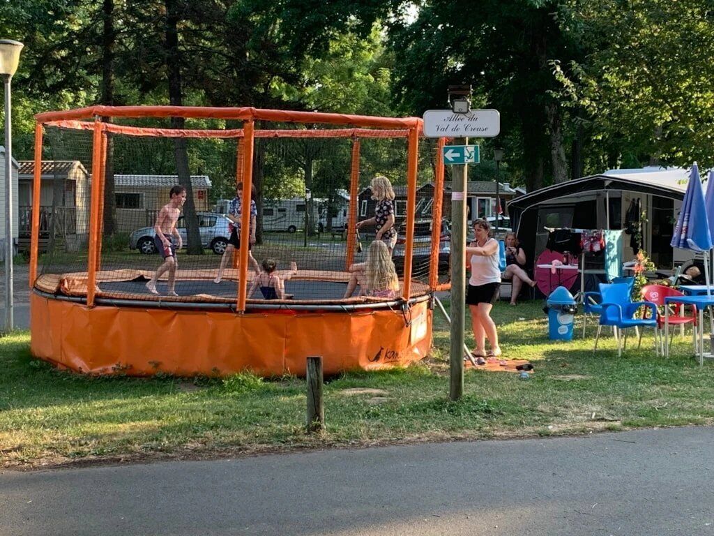 Un trampoline installé à l’extérieur, avec un panneau indiquant un endroit situé à proximité.