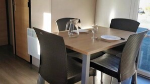 Un comedor con una mesa de madera, dos sillas, una jofaina y un extintor en la pared.