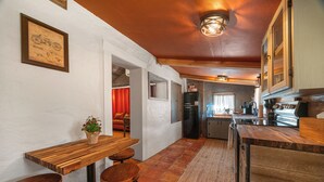 Une cuisine avec des plans de travail en bois, un réfrigérateur et un évier. On y trouve également un coin repas avec une table et des tabourets en bois.