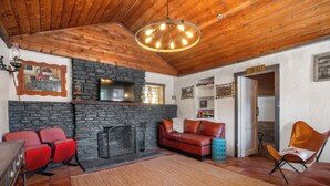 Un salon chaleureux avec une cheminée en pierre, un plafond en bois et des meubles en cuir rouge.