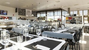 A restaurant with tables set for dining, a bar area, and a kitchen in the background. - ZEcamping 3 étoiles pataugeoire 200m plage pet friendly locatif TV (Cambrils)