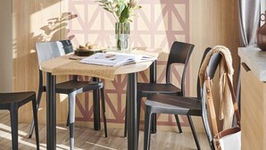 Ein moderner Essbereich mit einer Wand mit geometrischem Muster, einem Holztisch und schwarzen Stühlen.