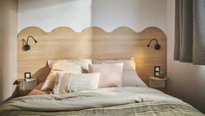 Ein Schlafzimmer mit einem hölzernen Kopfteil, zwei Nachttischlampen und einem Bett mit vielen Kissen.