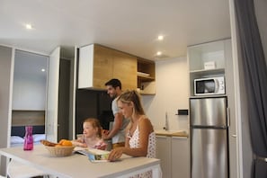 A modern kitchen with a dining table, a microwave, and a refrigerator.