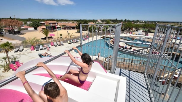 Zona junto a la piscina con una plataforma de salto, sillas de descanso y vistas al paisaje circundante.