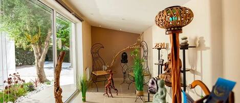 A modern interior with a glass wall, a wooden sculpture, and a Buddha statue.