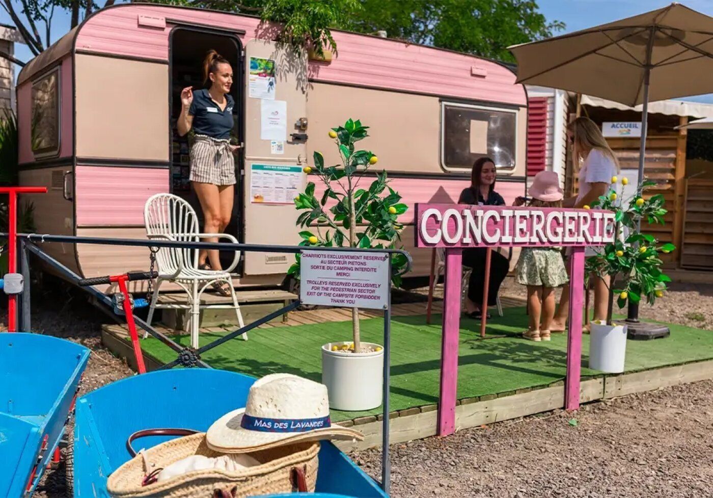 A pink RV with a sign reading 'CONCIERGERIE' and a sign indicating 'CHARIOTS EXCLUSIVELY RESERVED FOR THE PEDIATRIC SECTOR THANK YOU FOR YOUR PATRONAGE.'