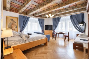 A room with a wooden bed, a desk, a chair, a TV, and a painting on the wall. - At the Blue Lion & Parking Assistance (Prague)