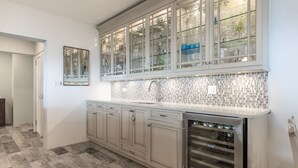 A kitchen with a tiled backsplash, a built-in oven, and a glass-fronted cabinet above the sink.