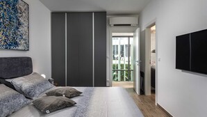 A bedroom with a bed, pillows, a wardrobe, a TV, and a balcony with a view. - Villa LUXOR with heated pool (Sveti Vid Miholjice)