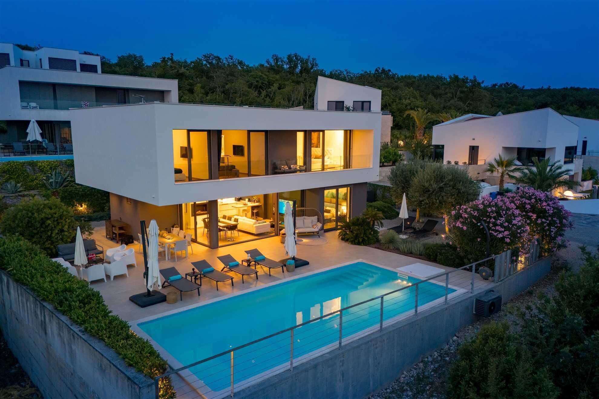 A modern two-story house with a swimming pool, outdoor seating, and a well-maintained garden.