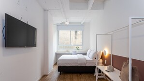 Ein modernes Schlafzimmer mit Bett, Nachttisch und einem an der Wand befestigten Fernseher.