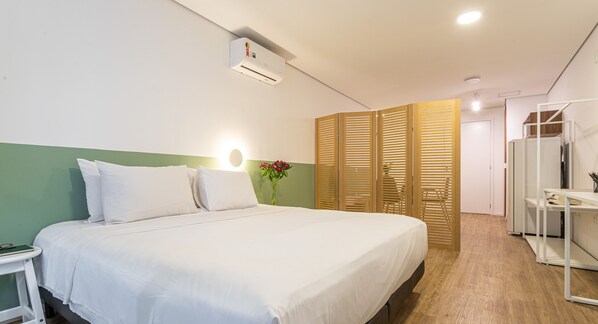 Een hotelkamer met een bed, nachtkastje en een spiegel.