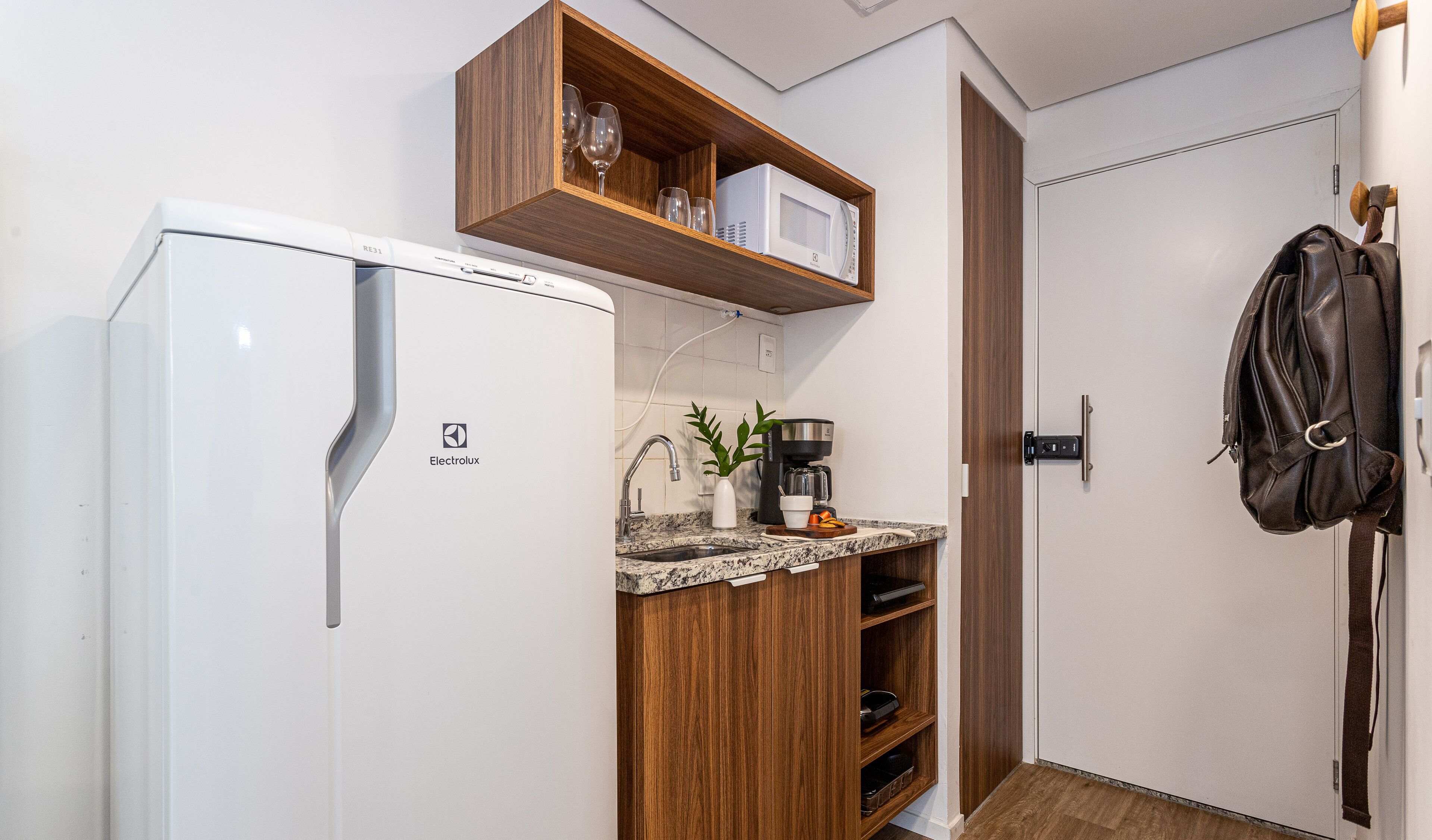 A compact kitchen with a white refrigerator, wooden cabinets, a microwave, and a coffee maker.
