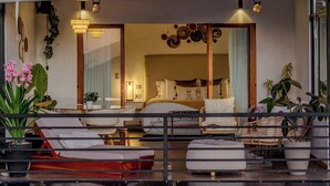 A modern hotel room with a large bed, a sitting area with a red sofa, and a balcony with potted plants. - Yaloco House Monteverde  (Sierra)