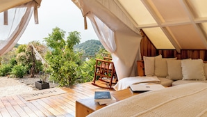 A tented accommodation with a wooden deck, a rocking chair, and a bed with pillows. - Yaloco House Monteverde  (Sierra)