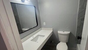 Een badkamer met een wit wastafel, toilet en spiegel.