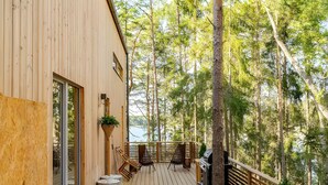 Une terrasse en bois offrant une vue sur un lac, entourée d’arbres.