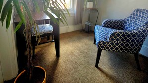A room with a large window, a potted plant, a blue patterned chair, and a painting on the wall. - Loft • King Bed • Free Parking • Early Check in 2pm / 12pm Late Check Out (Pottstown)