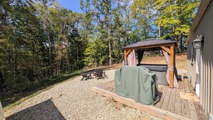 Un espace extérieur abrité avec une table et des chaises, un barbecue couvert et une terrasse en bois.