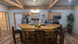 Une cuisine rustique avec des meubles en bois, un îlot central doté de tabourets et divers appareils de cuisine.