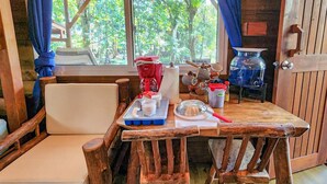 A rustic wooden dining table with a chair, a coffee maker, and kitchen utensils.