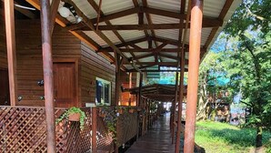 A covered wooden deck with benches and a gravel path leading to a cabin.