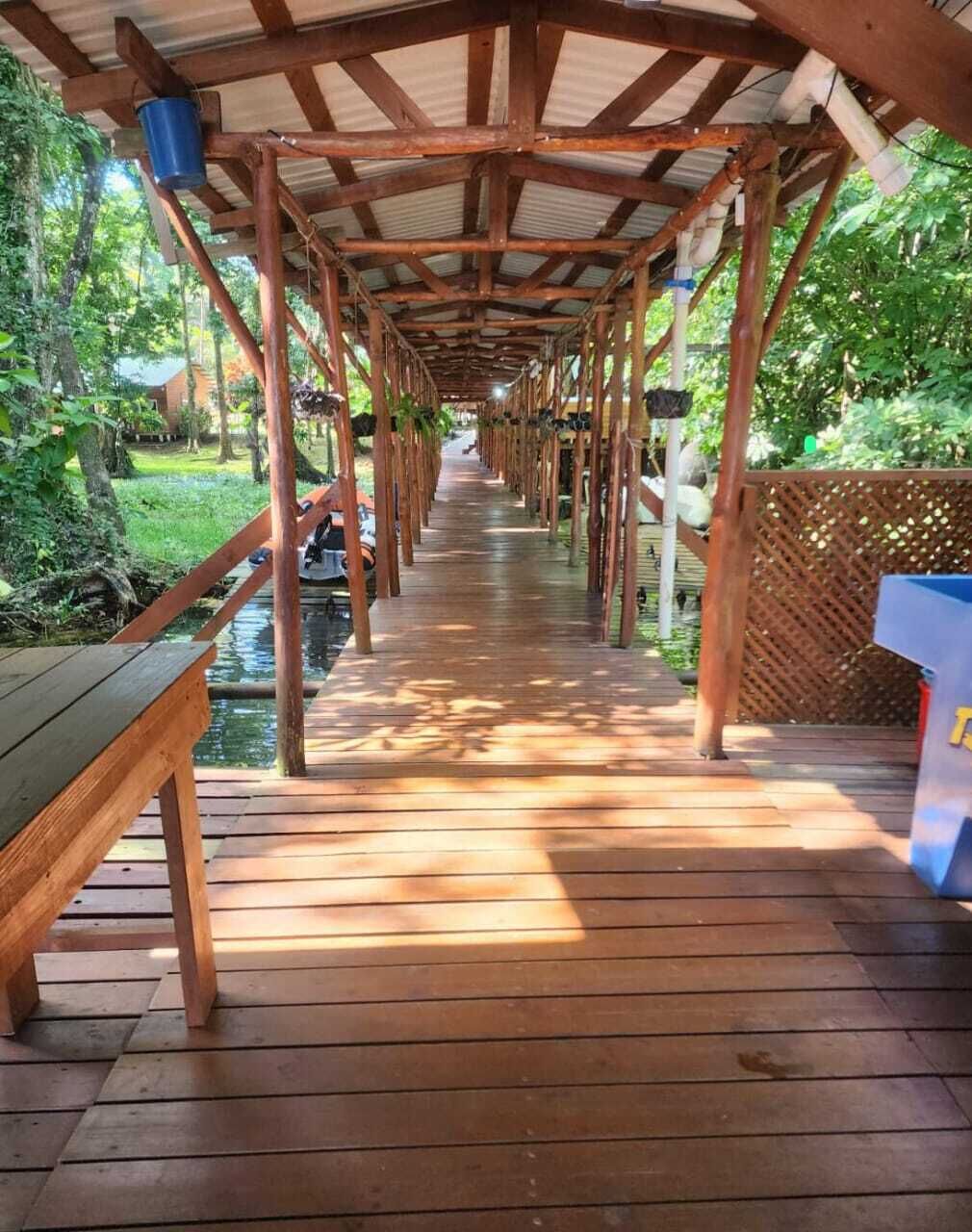 A wooden deck with a covered walkway, benches, and a small water feature.