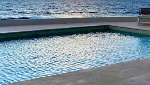 A pool with a view of the ocean and a sunset.