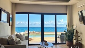 A living room with a large sliding glass door leading to a balcony with a view of the ocean.