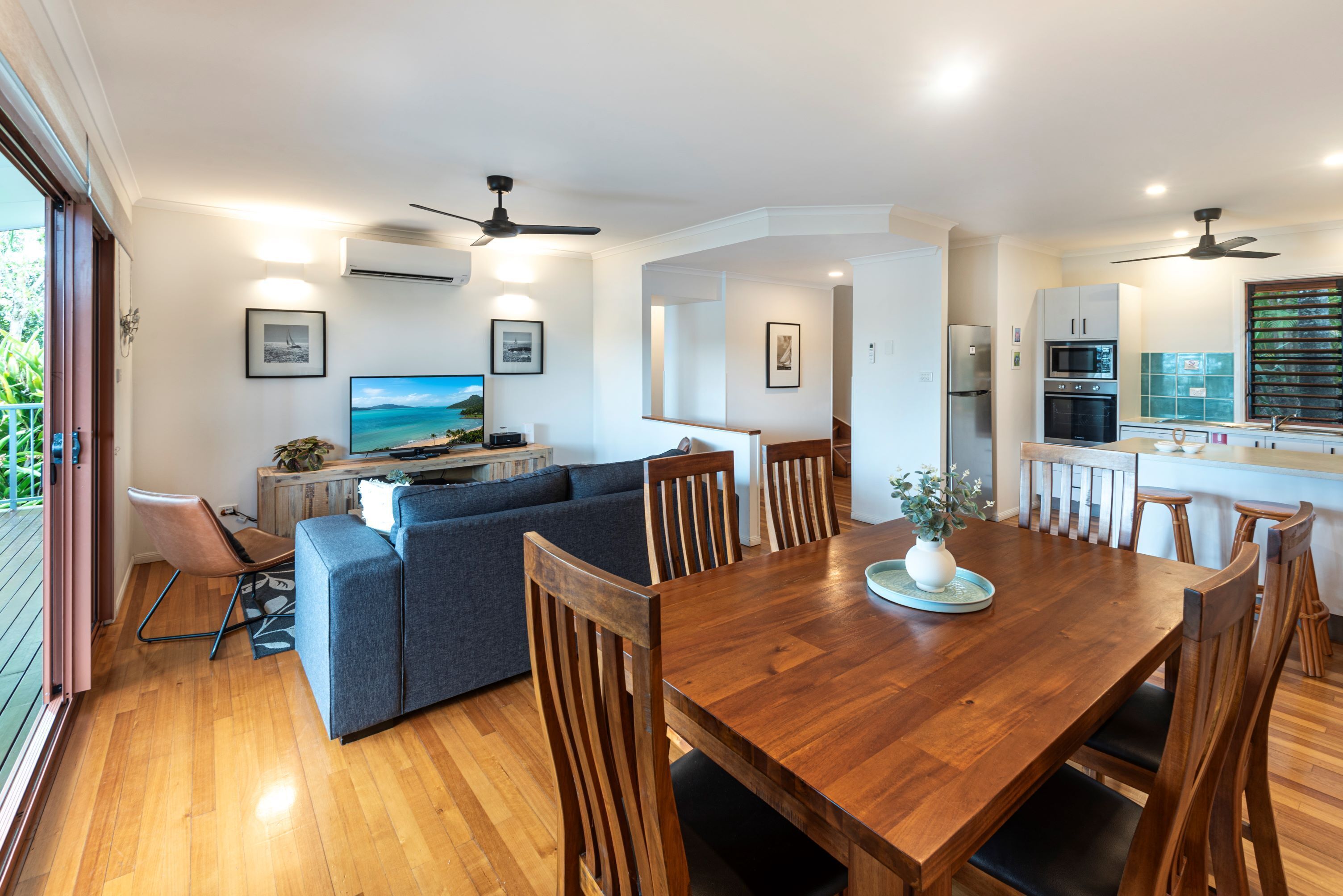 Una cocina moderna con zona de comedor, muebles de madera y un ventanal grande.