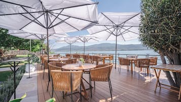 A deck with outdoor seating, umbrellas, and a view of the sea.
