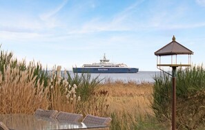 Un barco grande llamado 'Samsø Rederi' atracado en un puerto, con un pabellón y pastos altos al frente.