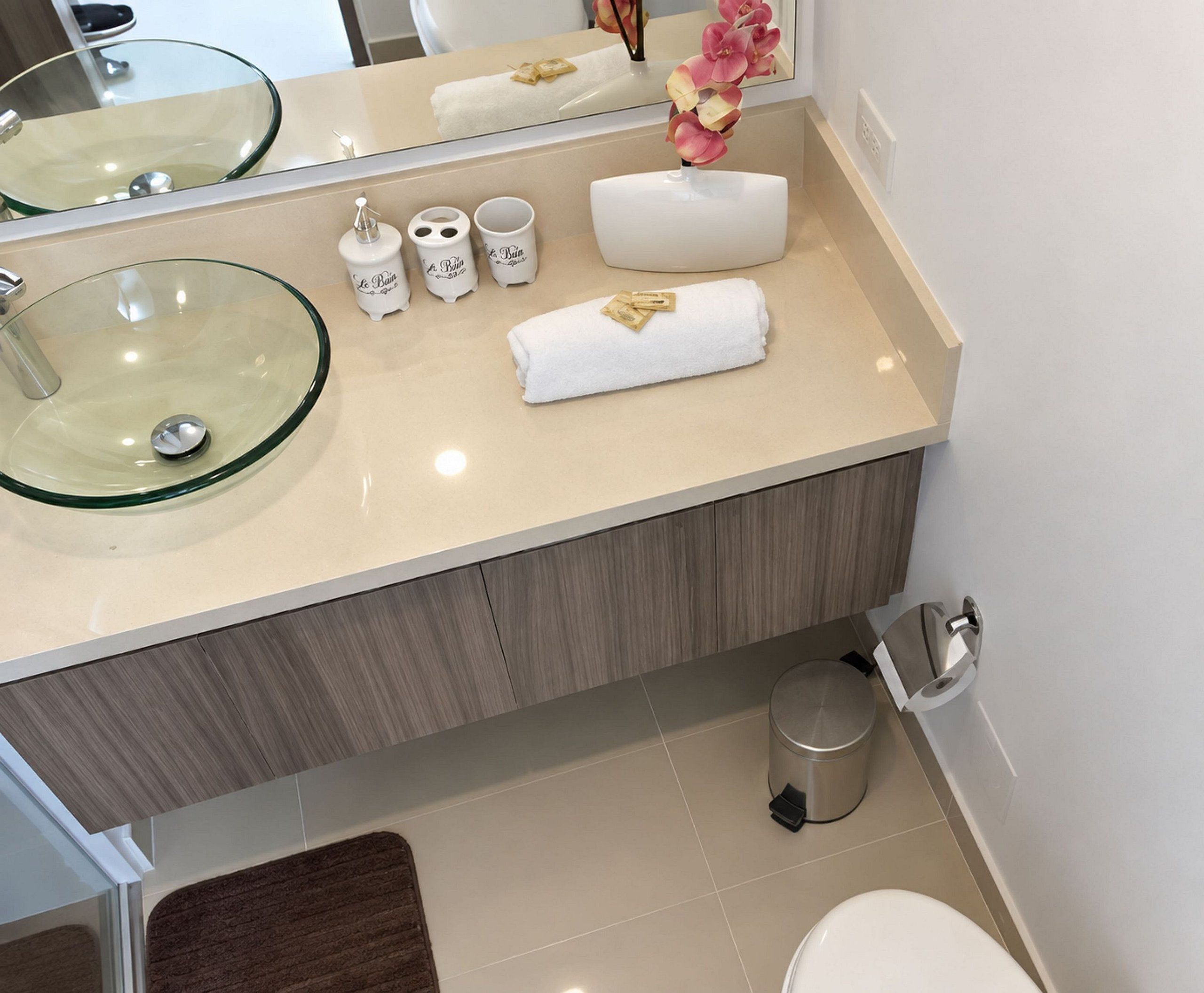 A bathroom with a glass sink, a towel, and toiletries.
