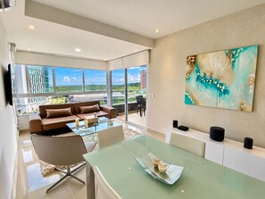 Ein modernes Wohnzimmer mit einem Glastisch, einer Couch und einem großen Fenster mit Blick auf die Stadt.