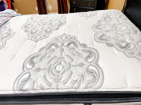 A bed with a white quilt featuring a detailed floral pattern.