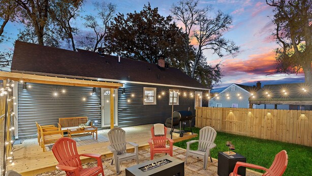 A backyard with outdoor furniture, a fire pit, and string lights.