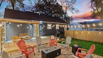 A backyard with outdoor furniture, a fire pit, and string lights.