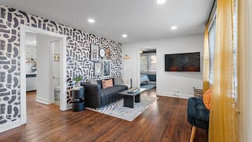 A modern living room with a black and white patterned wall, a dark sofa, a coffee table, and a blue armchair.