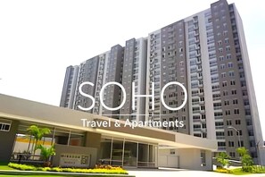 A modern building with multiple floors, a flat roof, and a sign indicating it is a travel and apartment complex. - Apartamentos Mirador - by SOHO (Puerto Colombia)