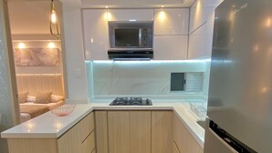 A modern kitchen with a central island, built-in microwave, gas stove, and stainless steel refrigerator. - Apartamentos Mirador - by SOHO (Puerto Colombia)