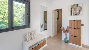 Ein Flur mit einer Bank, einem Spiegel, einem Holzschrank und einem Fenster.