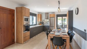 Eine moderne Küche mit Holzausstattung, einem eingebauten Ofen und einem Edelstahl-Kühlschrank.