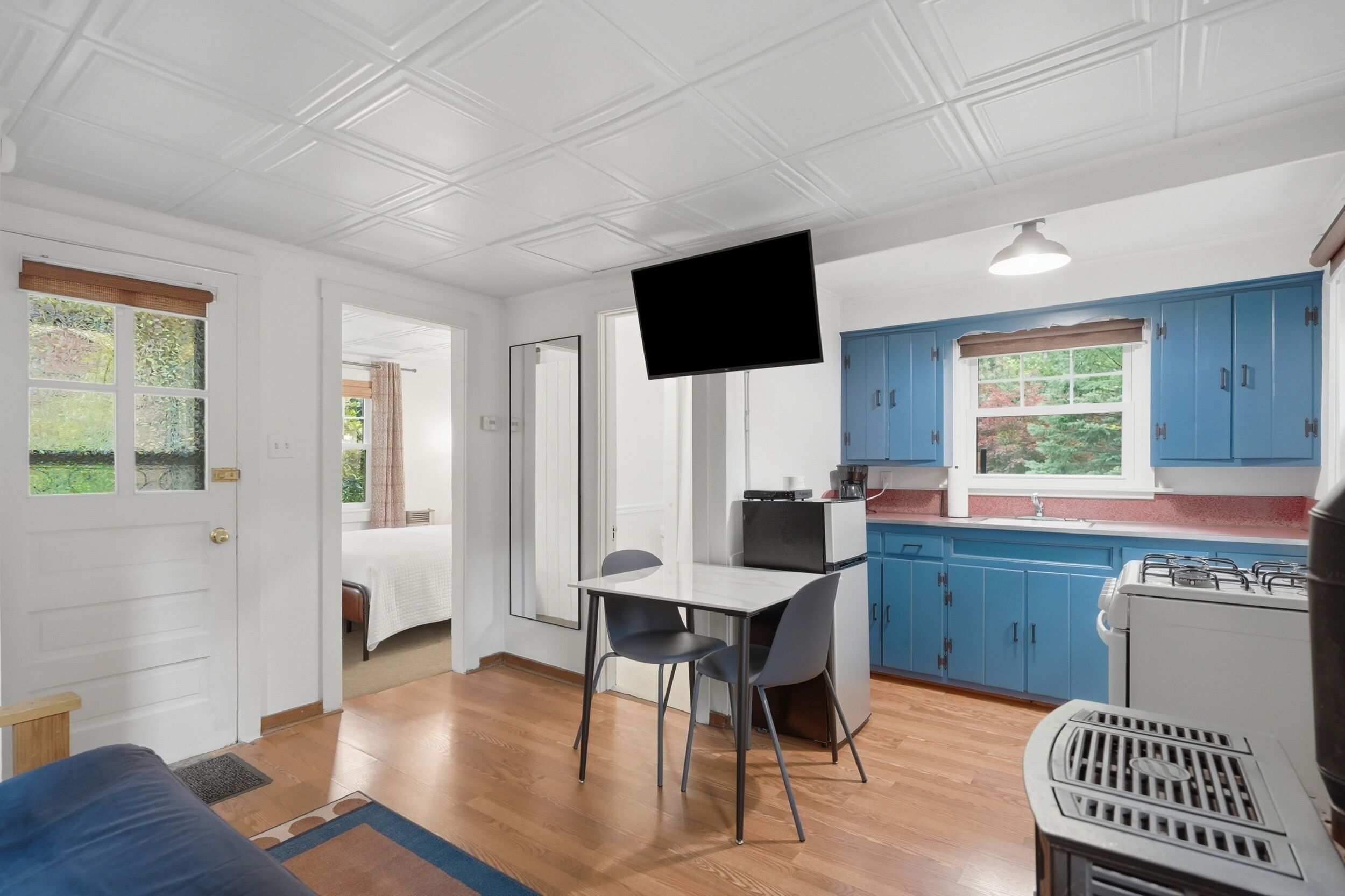 Un espacio habitable compacto con comedor, kitchenette y televisor.