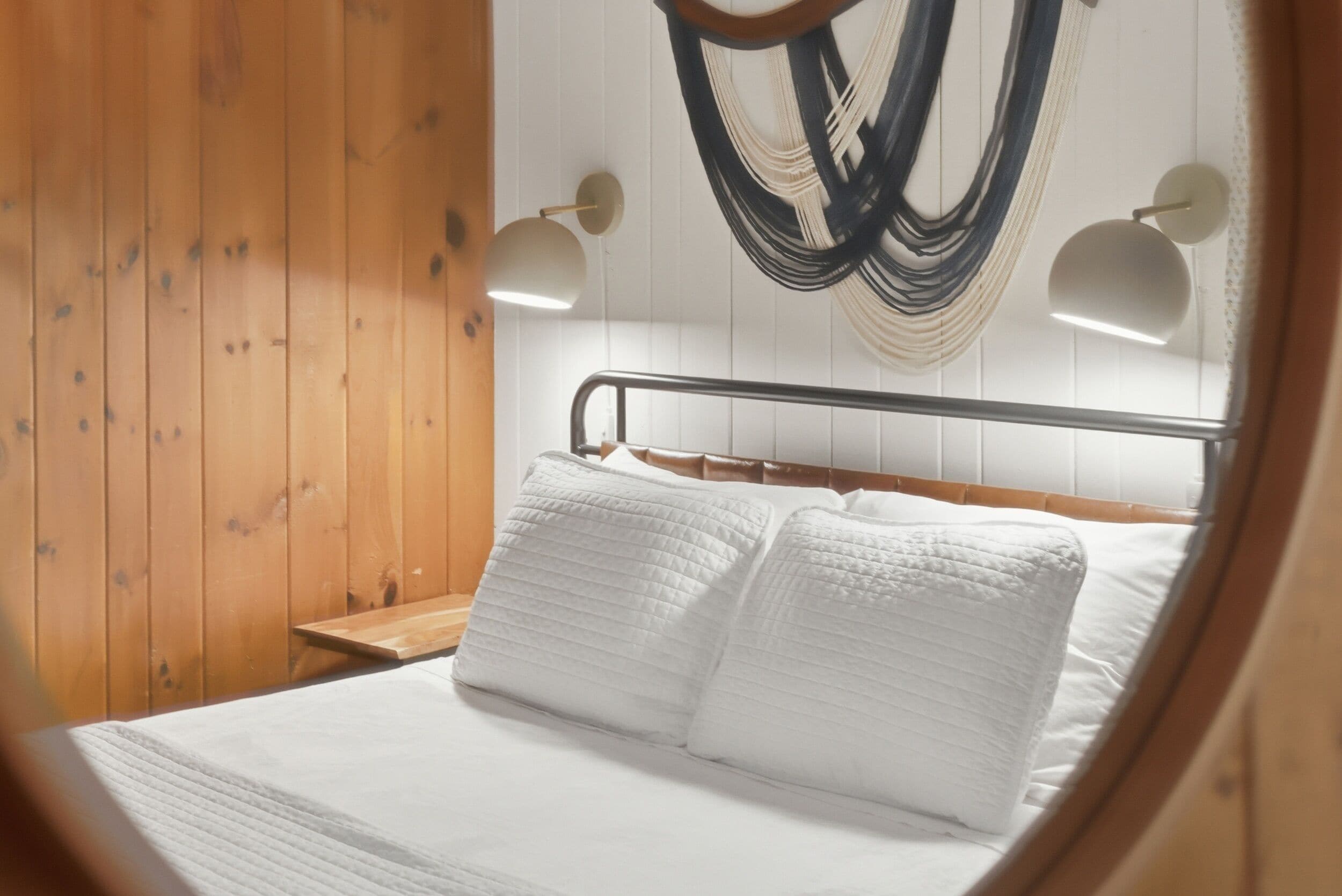 A bed with white bedding, a wooden headboard, and two bedside lamps.