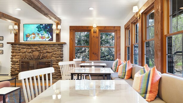 A dining area with a stone fireplace, wooden beams, and large windows. - Phoenicia Lodge (Phoenicia)