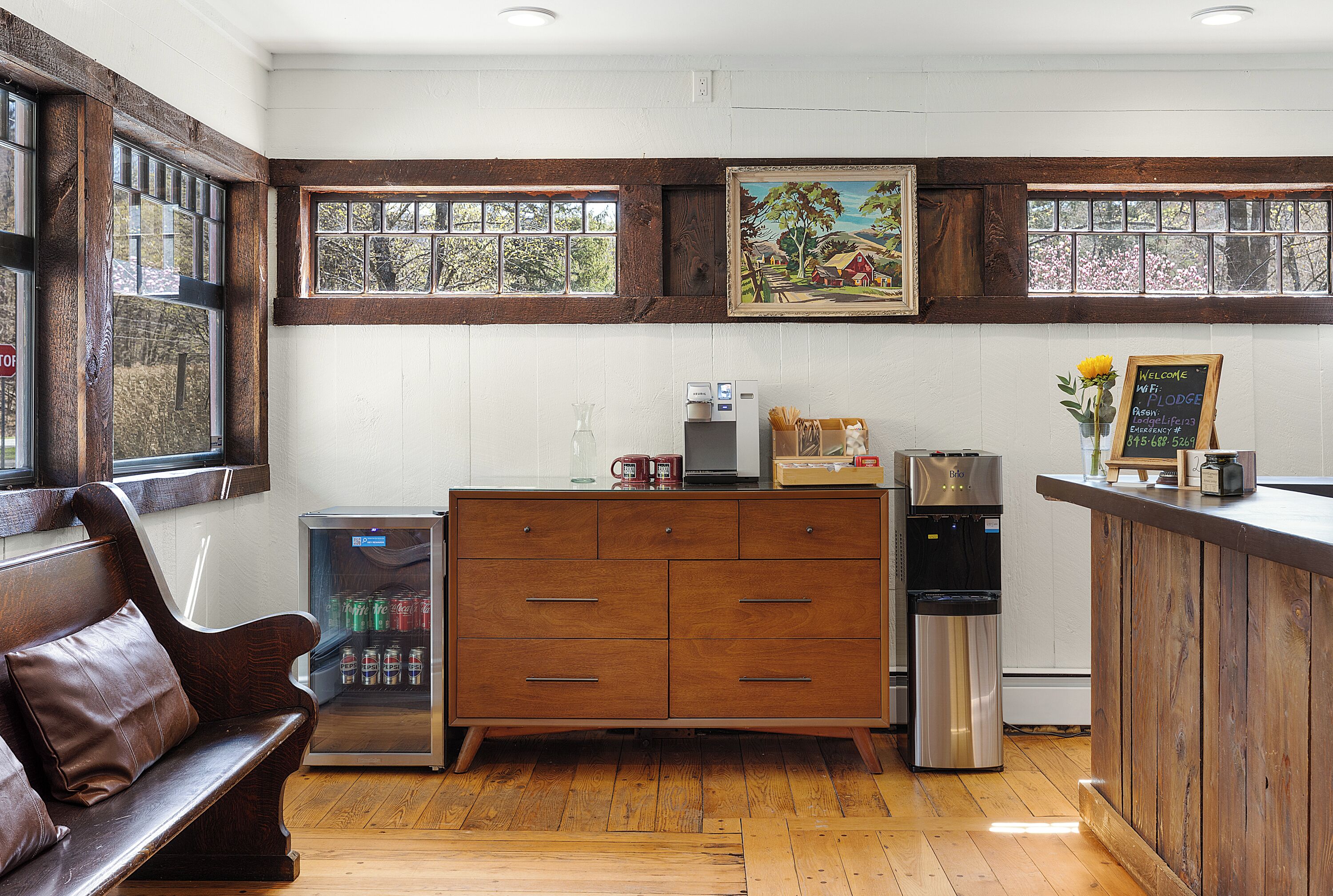 A kitchen with a wooden cabinet, a refrigerator, a coffee machine, and a chalkboard sign.
