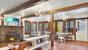 A spacious living room with a stone fireplace, wooden beams, and large windows. - Phoenicia Lodge (Phoenicia)