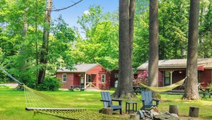 A hammock between trees, a red cabin, and a blue chair in a wooded area. - Phoenicia Lodge (Phoenicia)